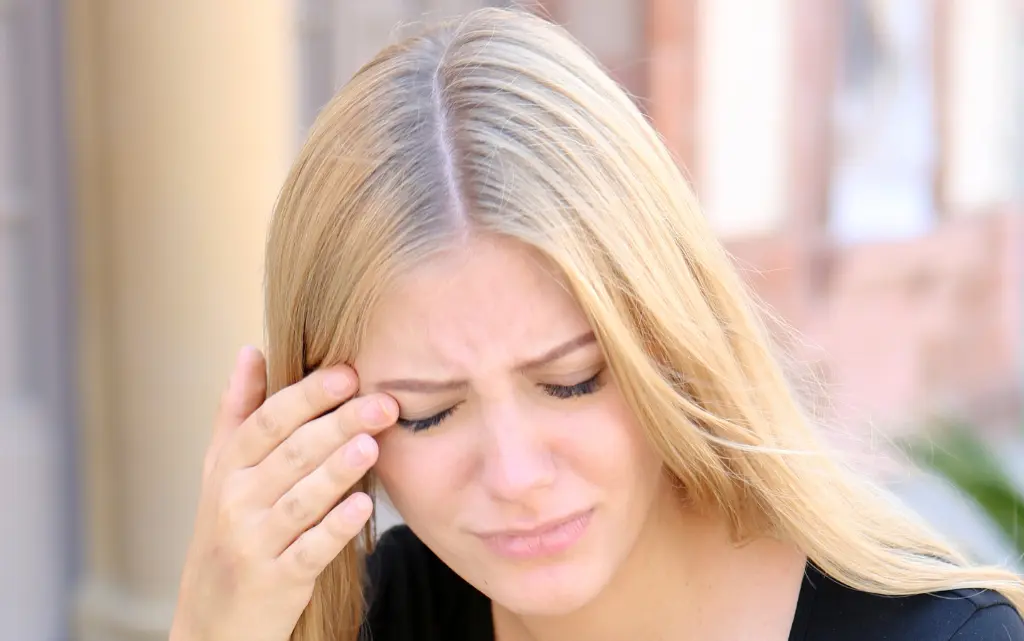 Kobieta ze smutną miną drapie się koło oka, bo są swędzi skóra