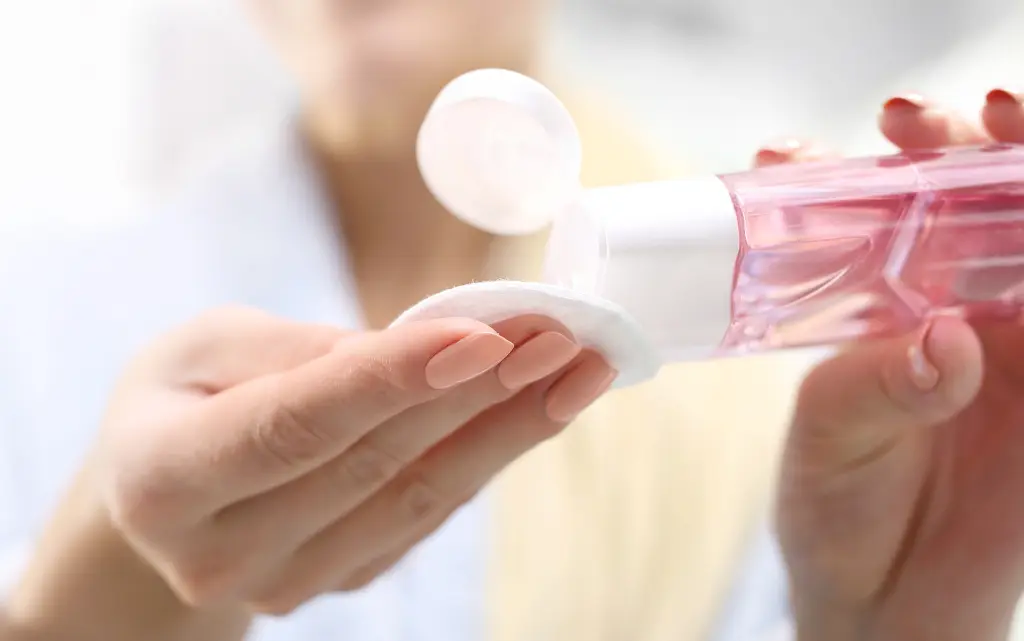 Kobiece dłonie nalewają na wacik kosmetyczny płyn do demakijażu