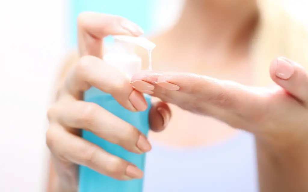 Kobiece dłonie aplikują na palce gęsty żel do demakijażu