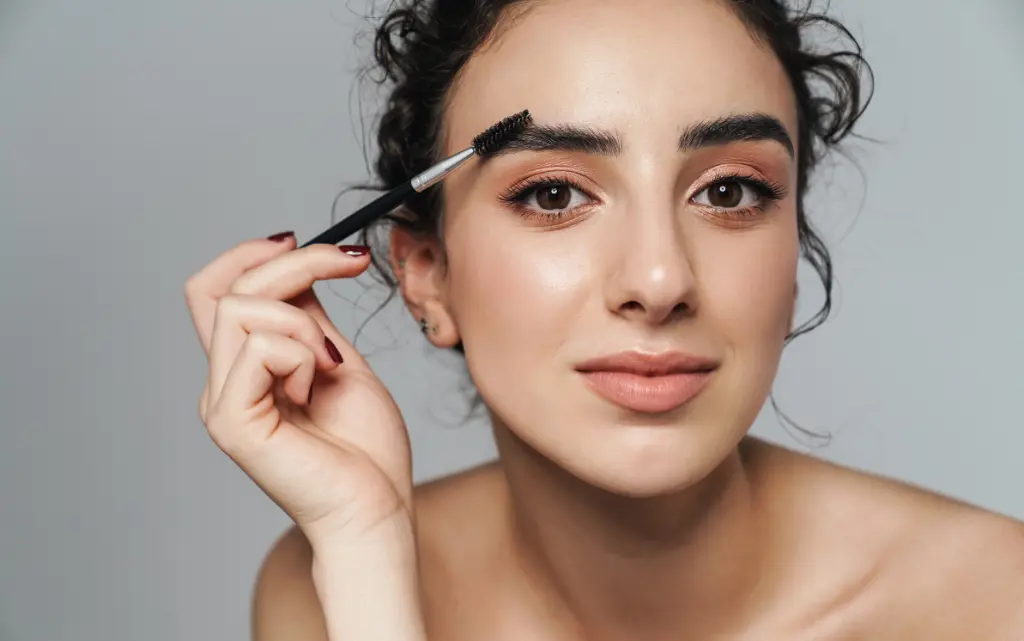 Młoda kobieta maluje brwi tuszem do rzęs