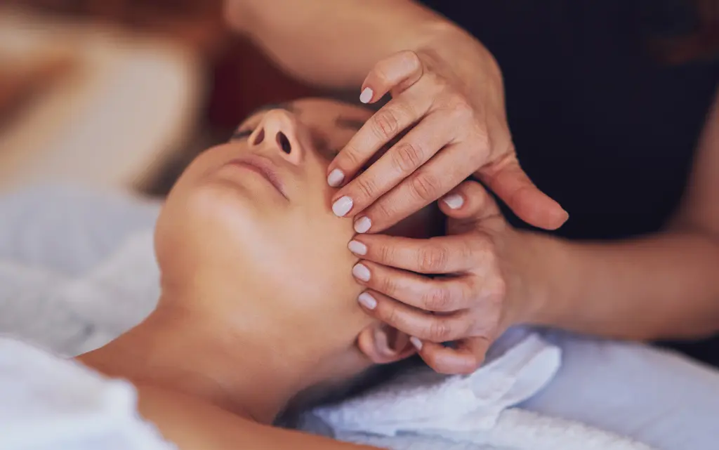 Kobieta wykonuje masaż twarzy u klientki w salonie kosmetycznym