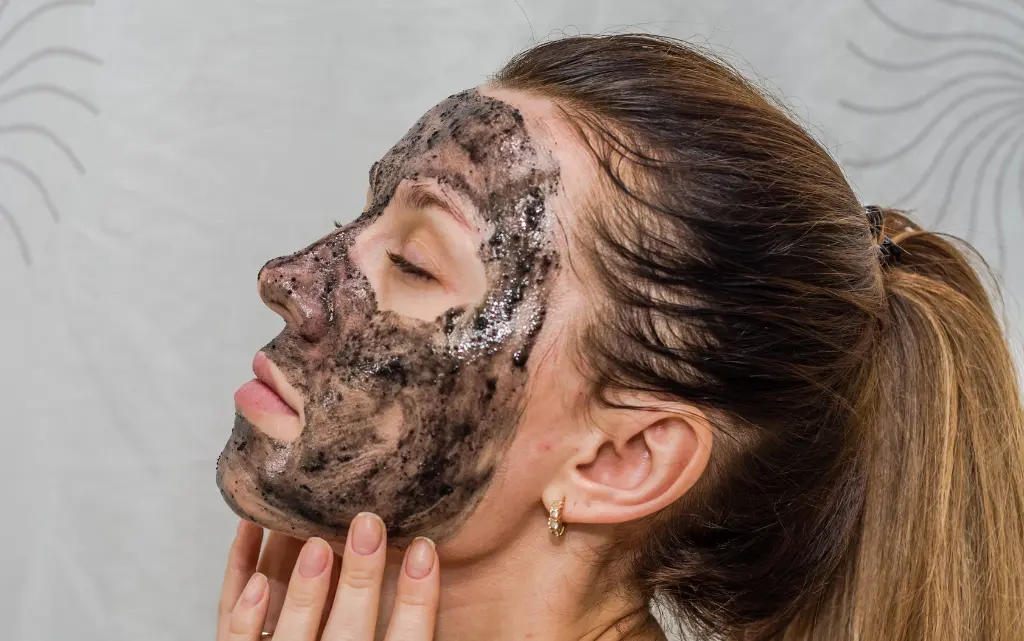 Boczny profil młodej kobiety z maseczką z węgla aktywnego na twarzy