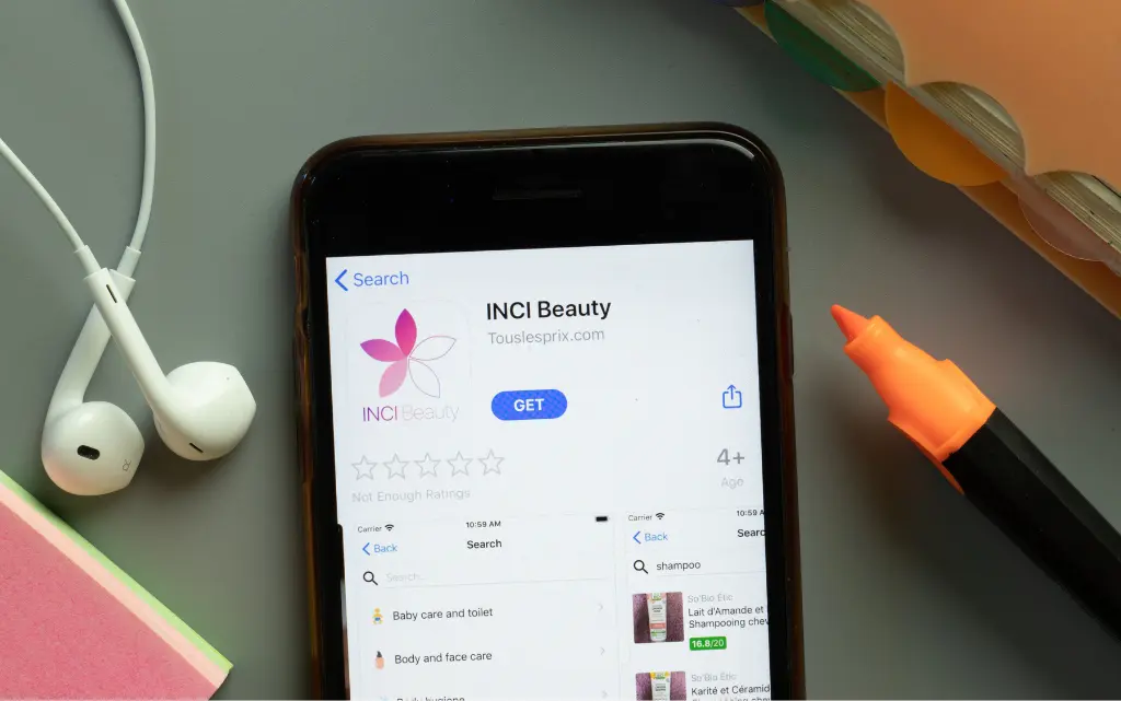 Biuro, na nich zakreślacz, słuchawki i smartfon z aplikacją INCI do sprawdzania składu kosmetyków