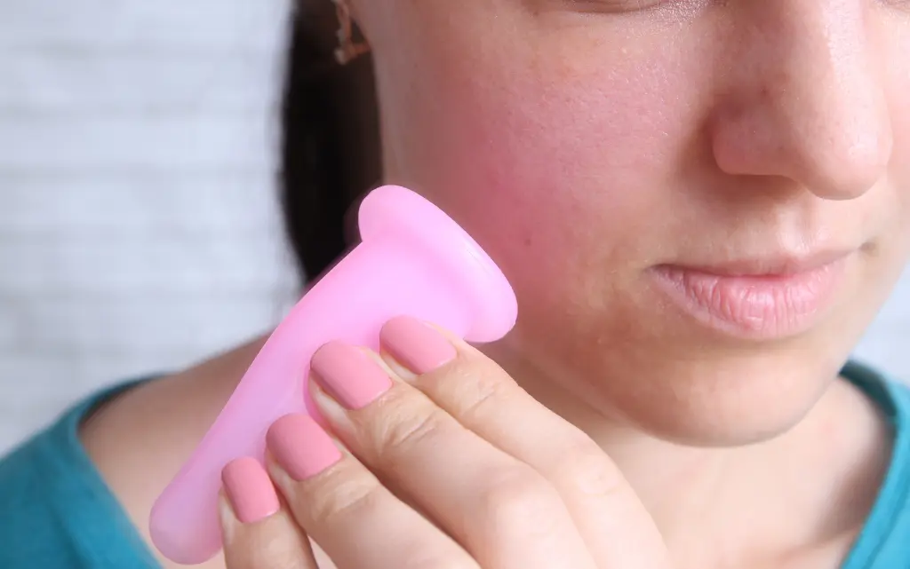 Zbliżenie na twarz kobiety trzymającej chińską bańkę silikonową do masażu twarzy