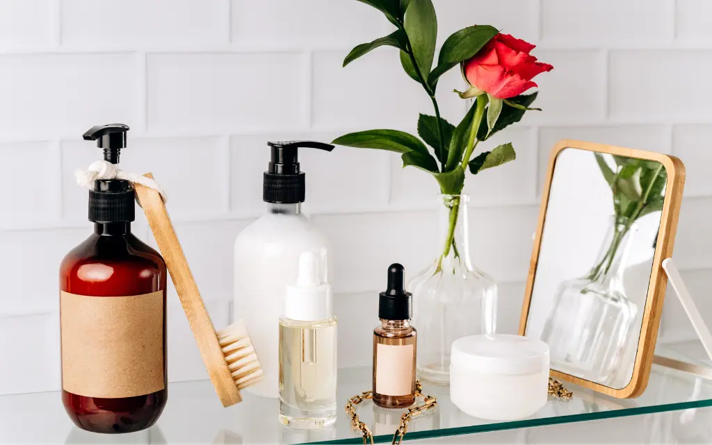 Rożnego rodzaju kosmetyki, mydła i serum, stojące na szklanej półce w łazience, w tle białe płytki