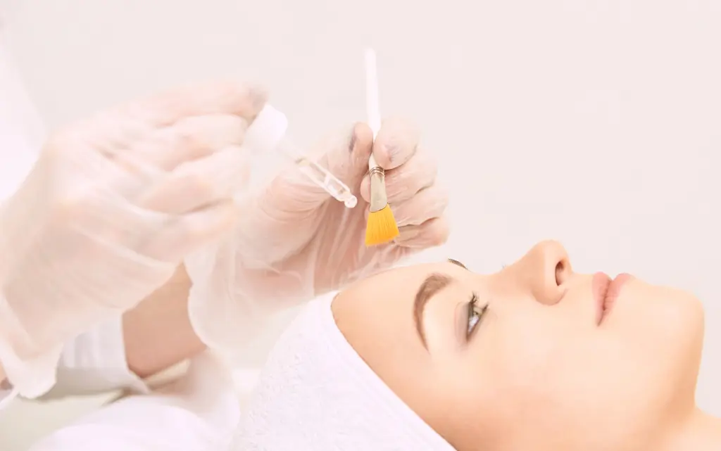 Kobieta w salonie kosmetycznym wykonuje kwasowy peeling twarzy