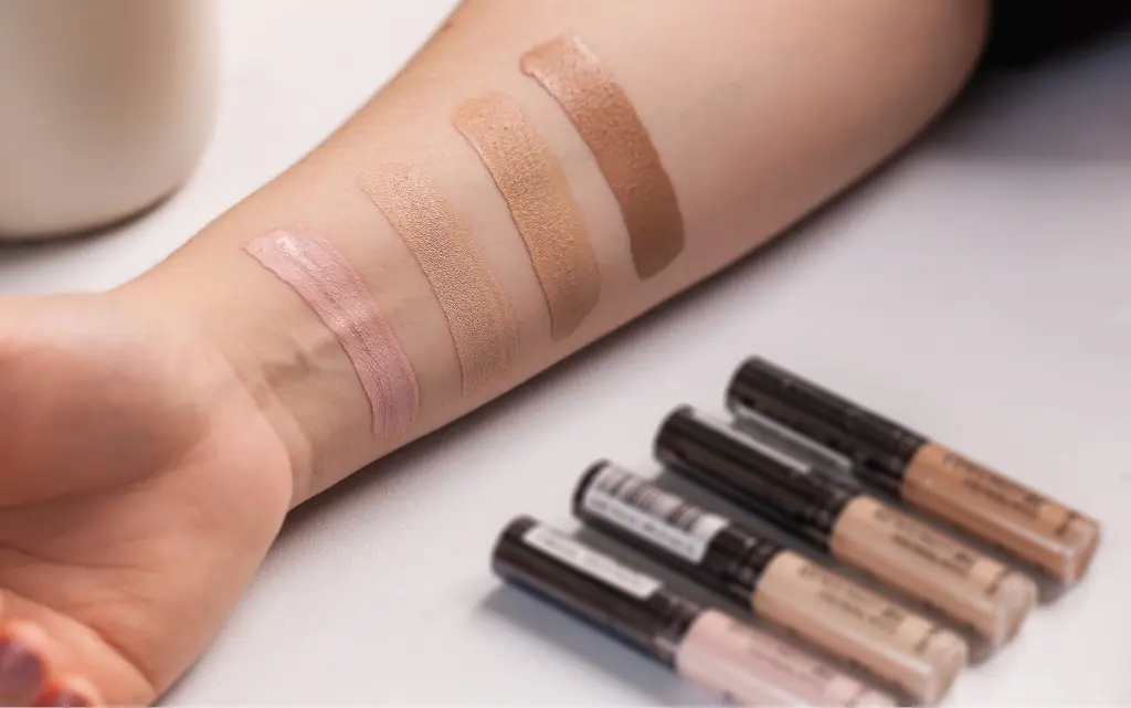 Wyciągnięta ręka, na niej cztery próbki różnych kolorów podkładów