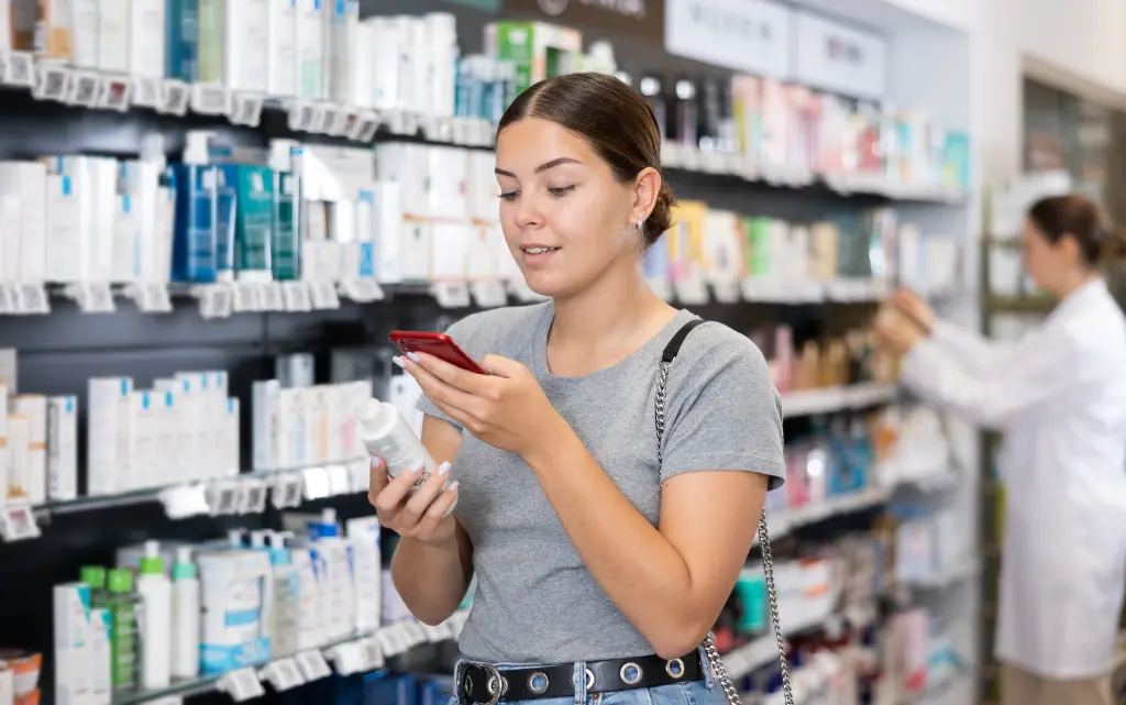 Nastolatka w drogerii czyta informacje na temat kosmetyku do makijażu