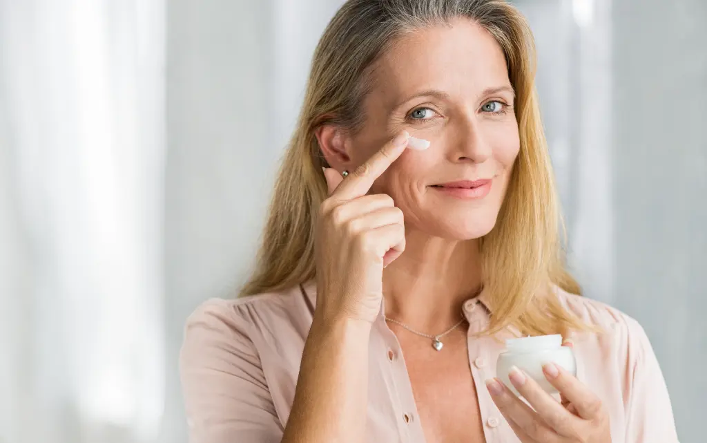 Kobieta w średnim wieku nakłada krem nawilżający do twarzy