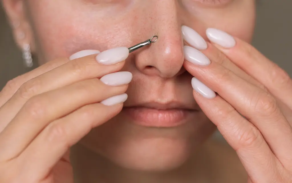 Kobieta mechanicznie usuwa zaskórniki z twarzy przy użyciu specjalnej łyżeczki unny