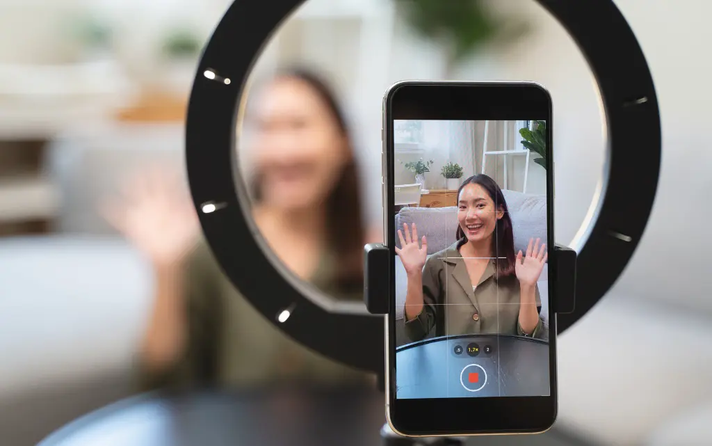 Zdjęcie smartfona przymocowanego do oświetlenia pokazujące streaming nastolatki w social mediach