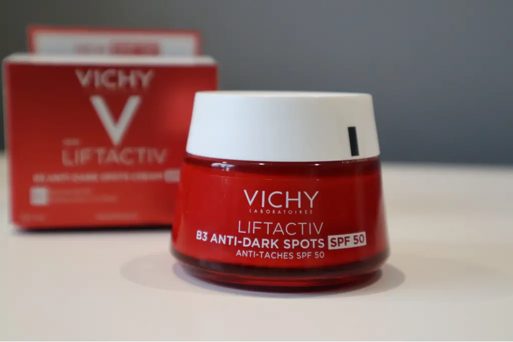 Vichy Liftactiv krem B3 SPF50 redukujący przebarwienia na tle opakowania i szarej ściany