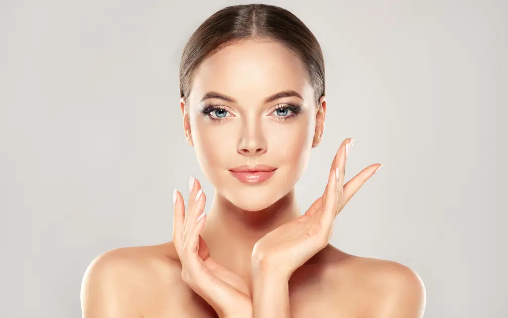 Młoda kobieta w makijażu glow up na beżowym tle