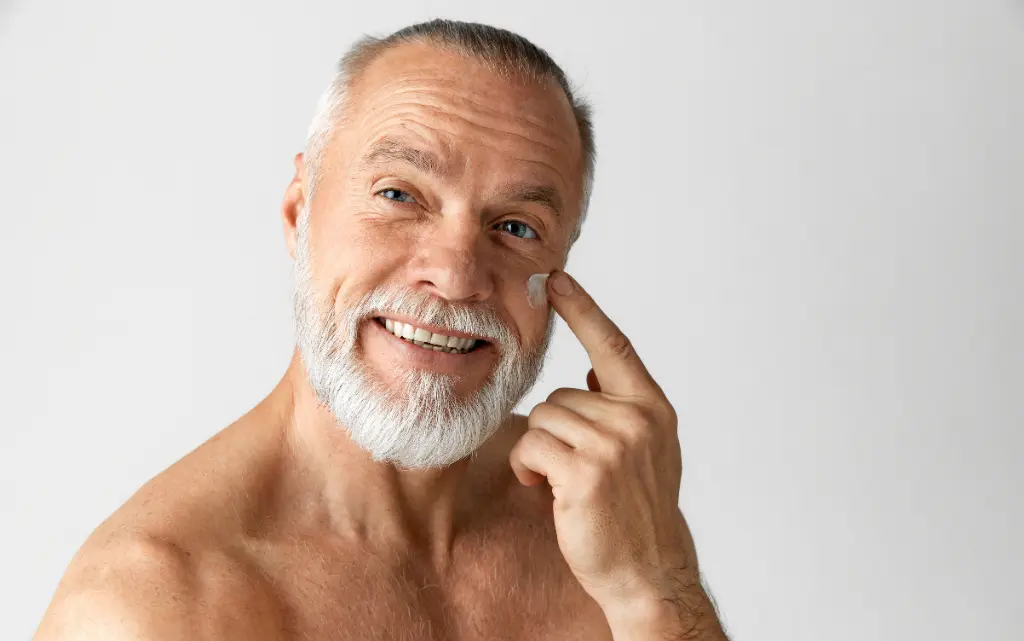 Starszy mężczyzna nakłada na twarz krem z SPF