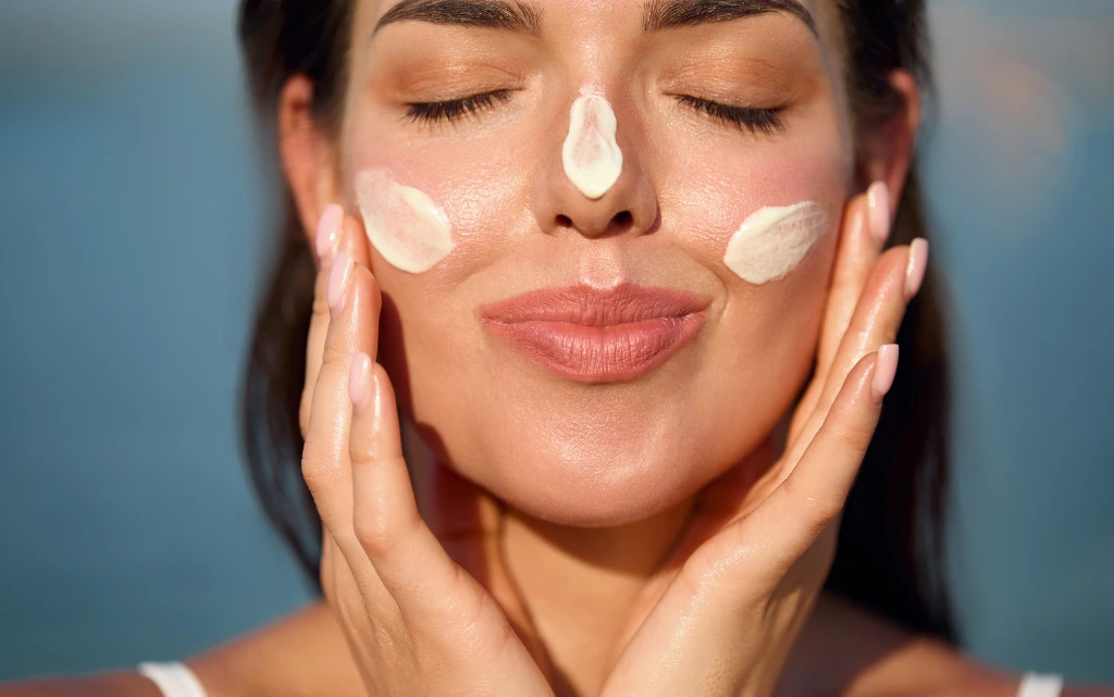 Zadowolona kobieta z kremem przeciwsłonecznym na twarzy