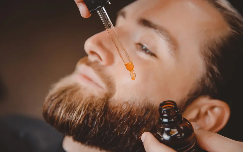 Mężczyzna u barbera nakłada olejek do brody