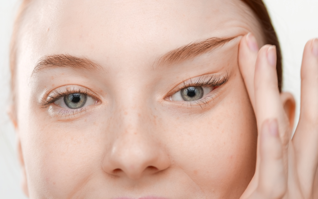 Młoda kobieta podnosi palcami opadającą powiekę
