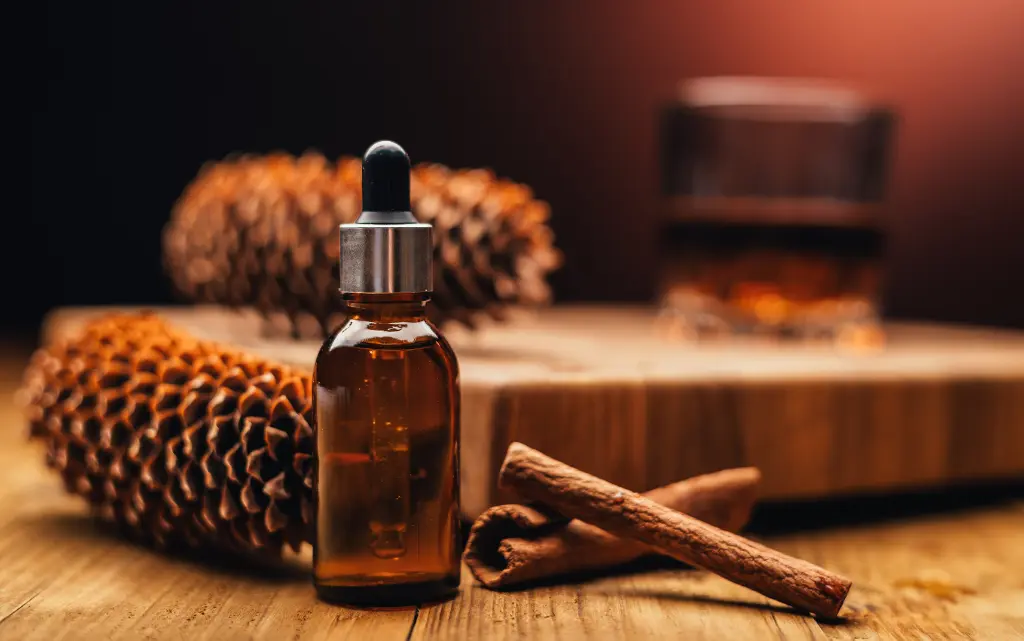 Olejek do brody w butelce, obok laski cynamonu i szyszki leśne wskazujące drzewny, intensywny zapach