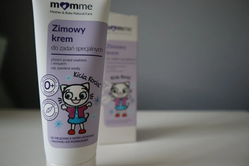 Tubka kremu Momme&Me. Kicia Kocia zimowy krem do twarzy na tle szarej ściany