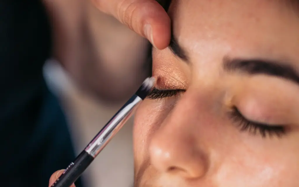 Makijażystka wykonuje makijaż oka u młodej kobiety