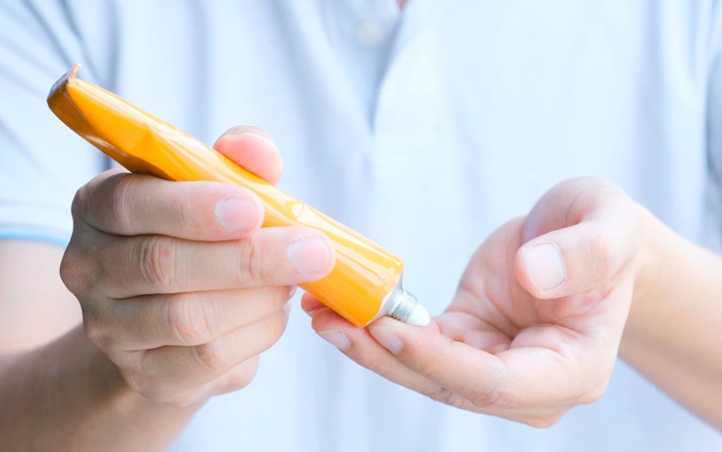 Kobieta nakłada na dłonie krem na atopowe zapalenie skóry twarzy