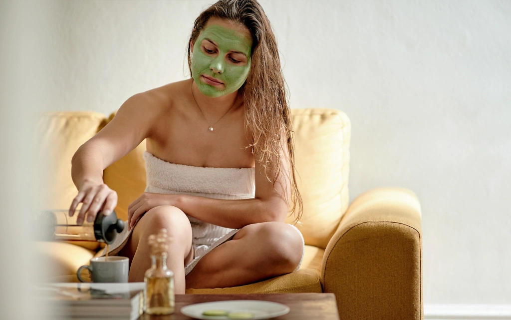 Kobieta w ręczniku w salonie i ma na twarzy maseczkę z zielonej herbaty
