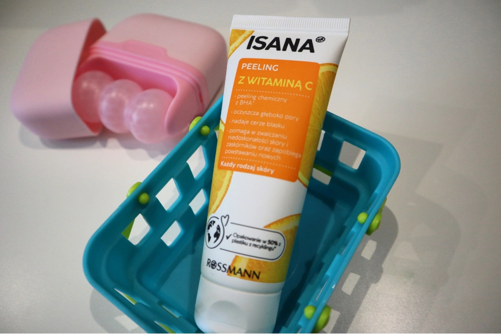 ISANA, peeling do twarzy, z witaminą C w niebieskim koszyczku, w tle masażer