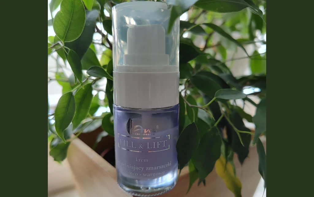 Szklane opakowanie kremu Ava Fill&Lift na tle zielonej rośliny