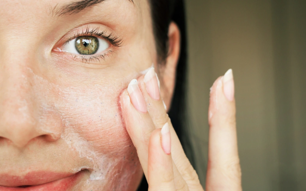 Uśmiechnięta kobieta nakłada krem na suchą cerę