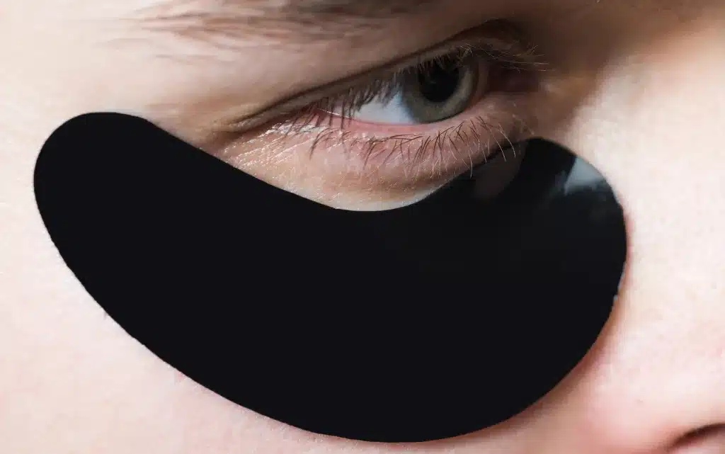 Zbliżenie na męskie oko z płatkiem przeciw opuchliźnie i cieniom pod oczami