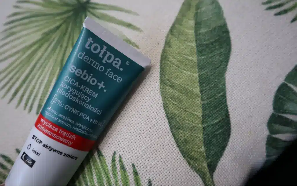 Krem na noc do cery trądzikowej Tołpa. Dermo face sebio+. korygujący niedoskonałości CICA leżący na zielono-beżowej poduszce