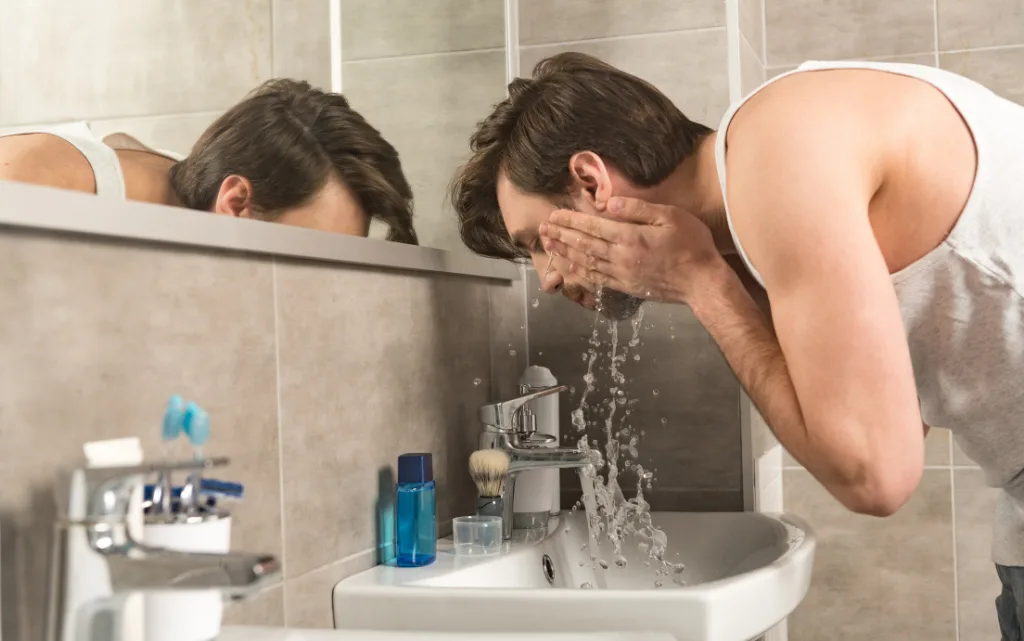 Mężczyzna w podkoszulce myje twarz z pomocą żelu do mycia twarzy dla mężczyzn