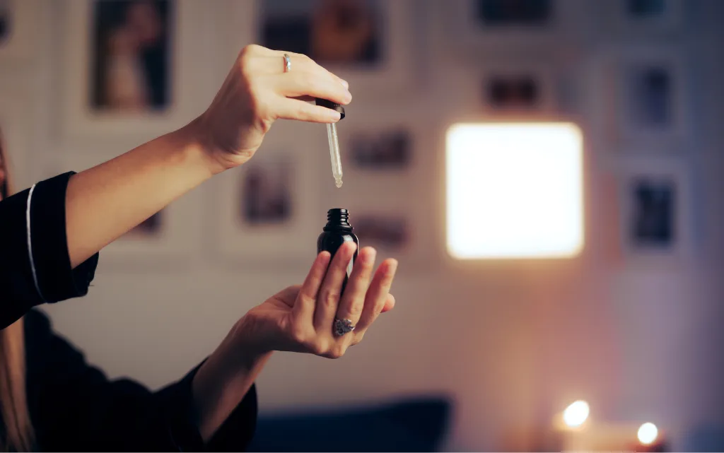 Kobiece dłonie trzymają otwartą butelkę z retinolem, w tle świecąca lampka