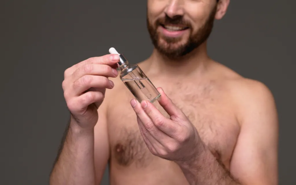 Mężczyzna trzyma w dłoniach butelkę serum do twarzy dla mężczyzn