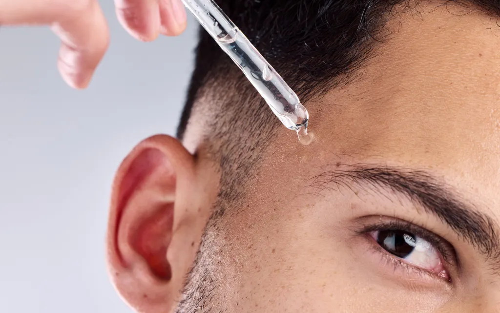 Zbliżenie na męską skroń, na którą nakłada się serum do twarzy dla mężczyzn