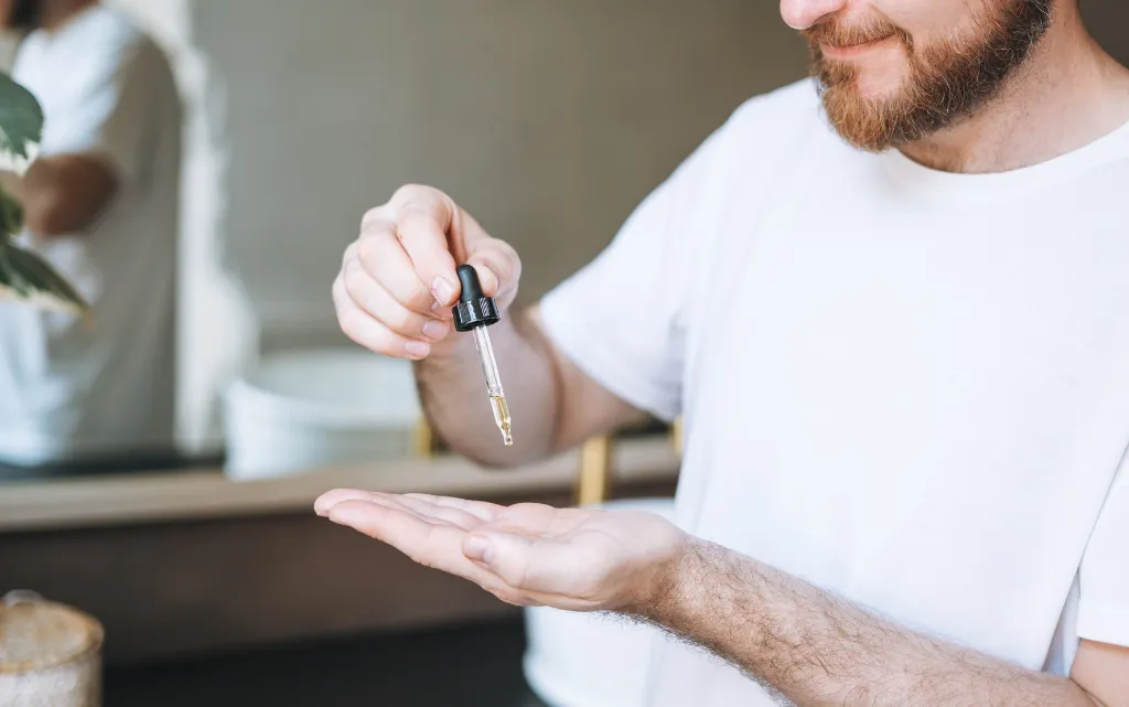 Mężczyzna nakłada na otwartą dłoń serum do twarzy dla mężczyzn