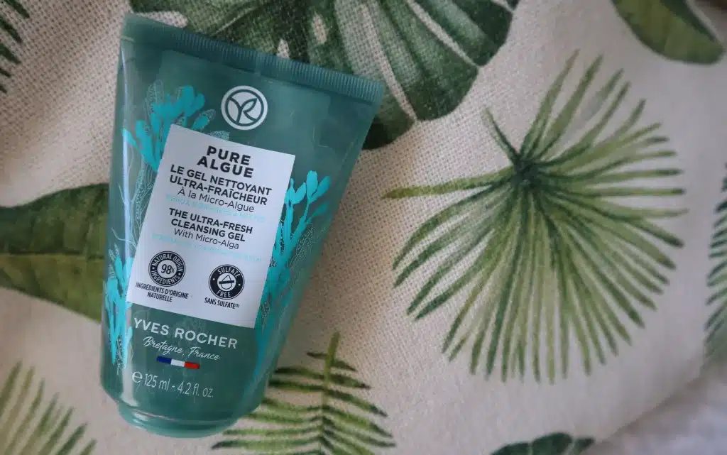Żel do mycia twarzy Yves Rocher Pure Algue na tle beżowo zielonej poduszki