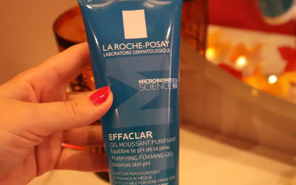 Kobieca dłoń trzymająca opakowanie żelu Effaclar na tle jesiennych dekoracji