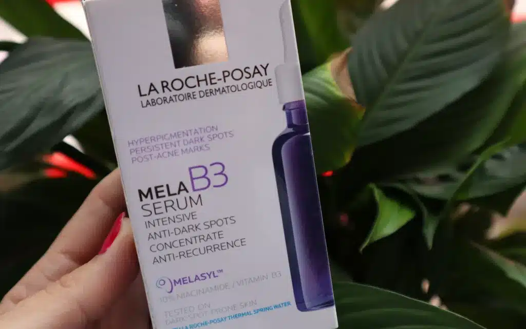 Opakowanie papierowe serum na przebarwienia La Roche Posay Mela B3 na tle zielonej rośliny