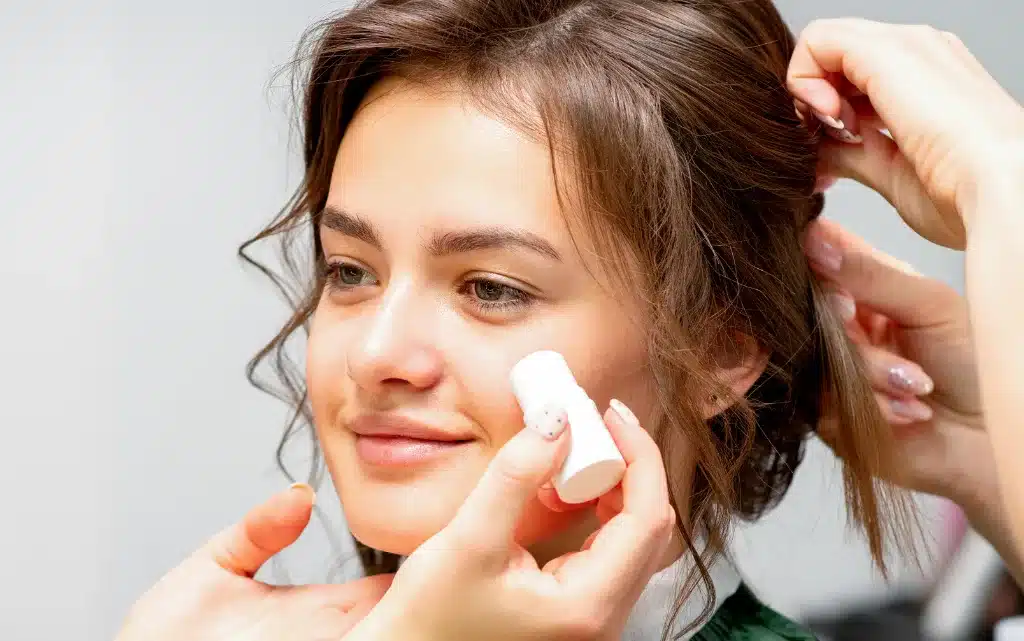 Młoda kobieta ma nakładaną bazę pod makijaż w sztyfcie