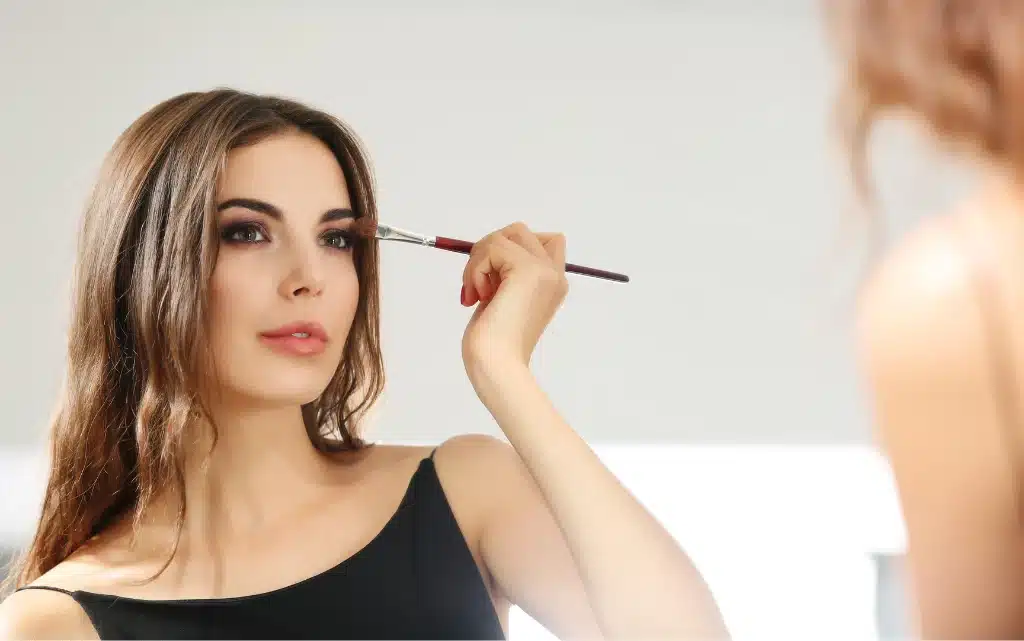 Młoda kobieta wykonuje makijaż oka w makijażu wieczorowym