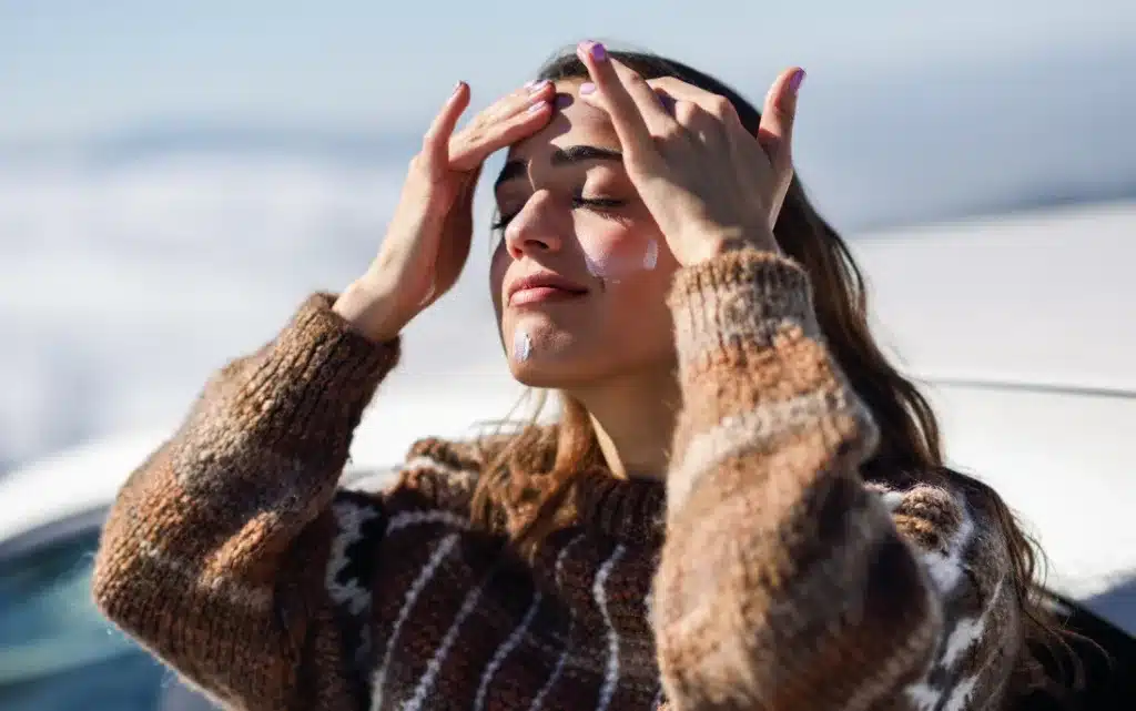 Kobieta smaruje twarz kremem ochronnym na zimę