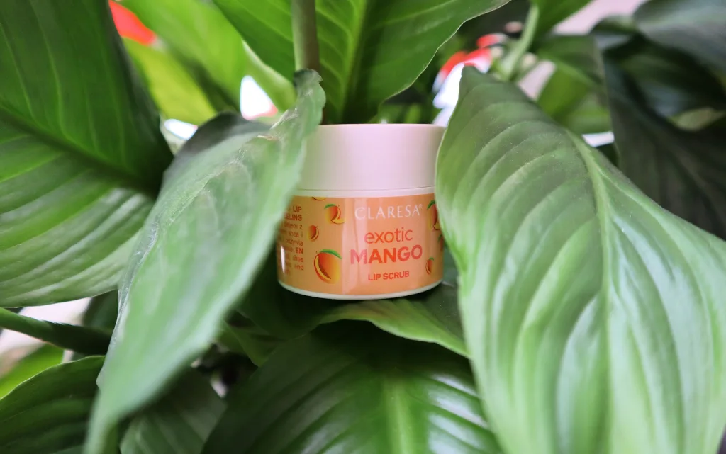Opakowanie peelingu do ust Claresa exotic mango na tle zielonej rośliny