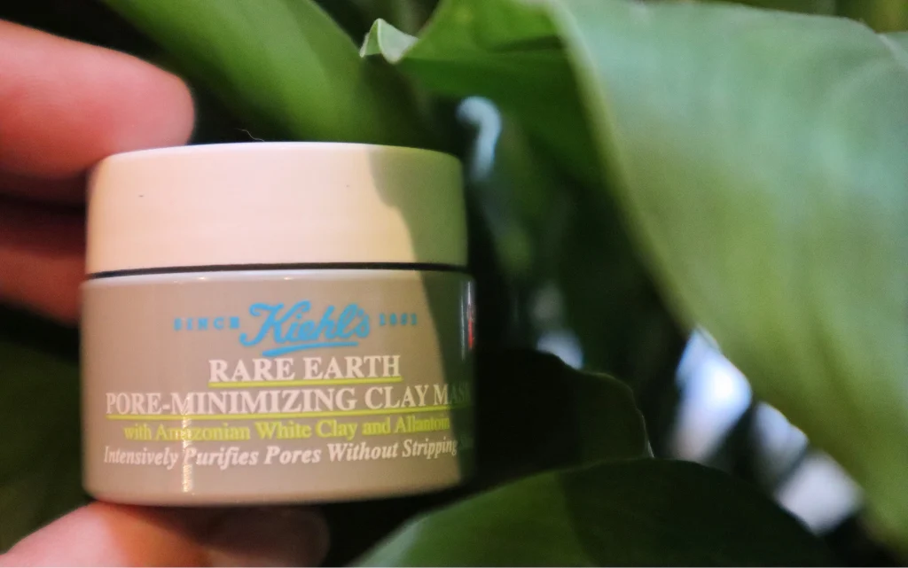 Maseczka z glinki Kiehl's Rare Earth Deep Pore Cleansing Mask na tle zielonych liści kwiatu