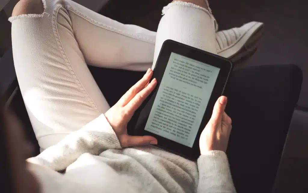 Siedząca kobieta czyta Ebooka o pielęgnacji cery w duchu skinminimalizmu