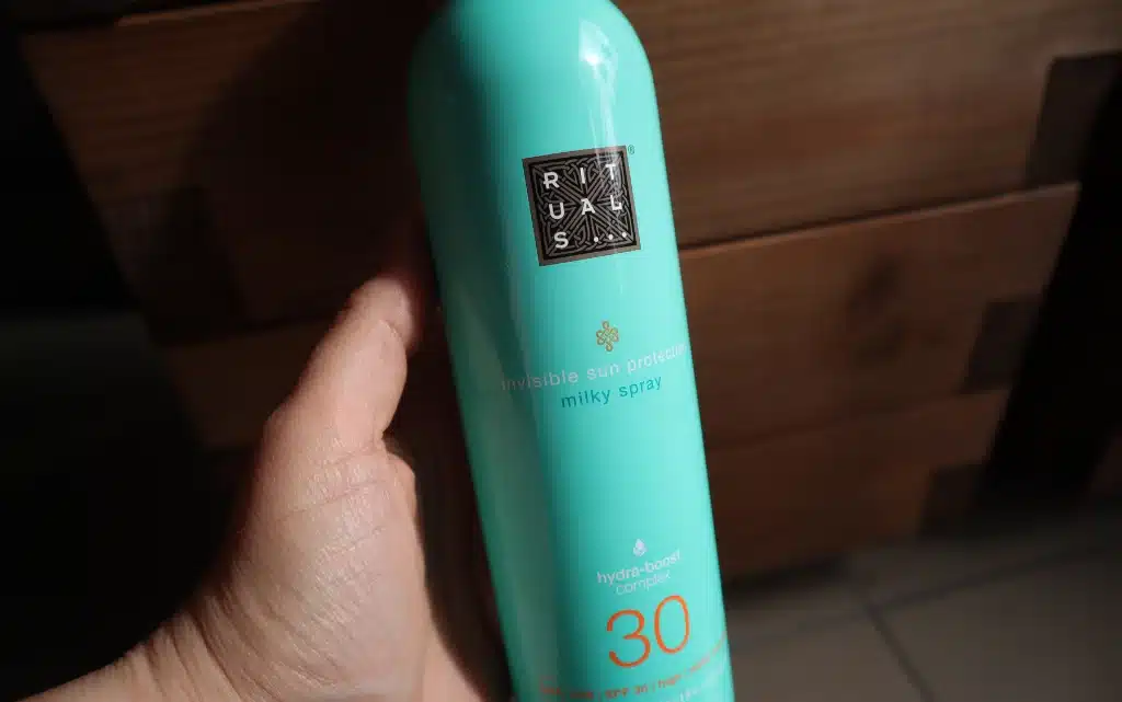 Dłoń trzyma Mleczko do opalania w sprayu The Rituals of Karma SPF 30