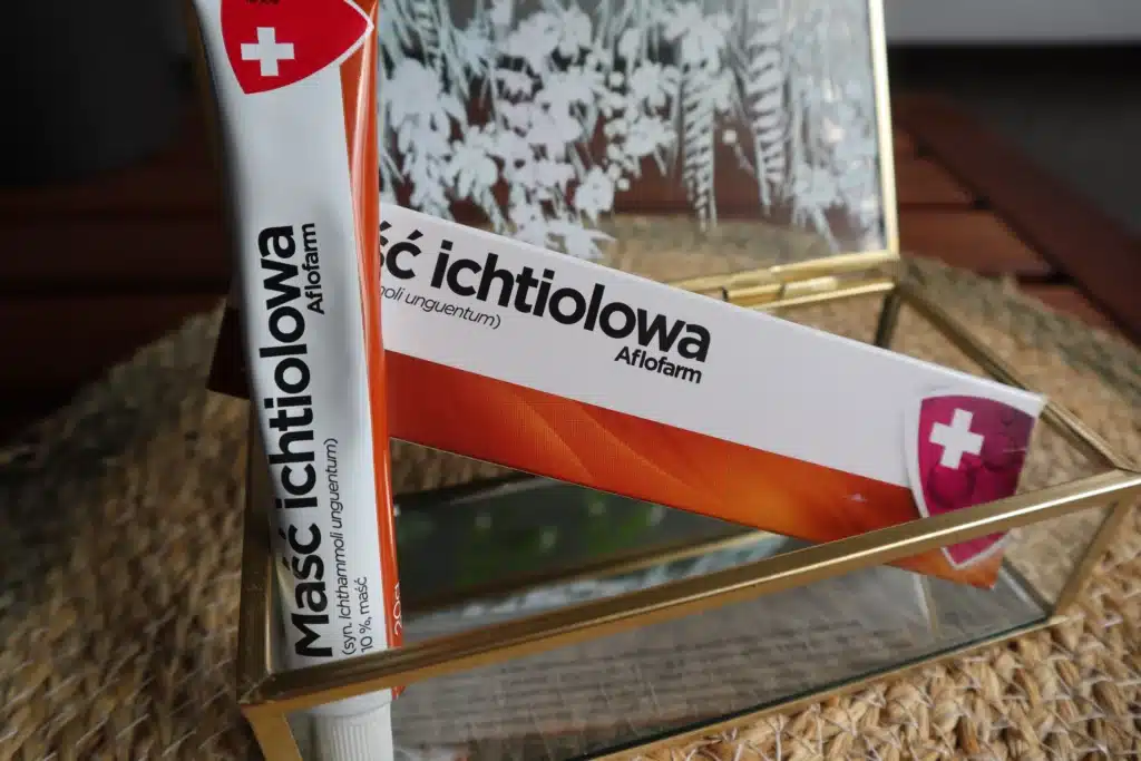 Aluminiowa tubka maści ichtiolowej obok papierowego kartoniku w dekoracyjnym pudełku
