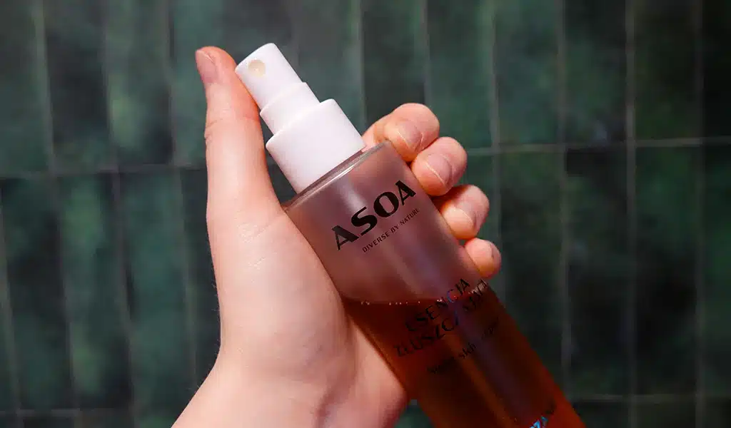 Esencja złuszczająca ASOA night skin repair w kobiecej dłoni, w tle zielone płytki w łazience
