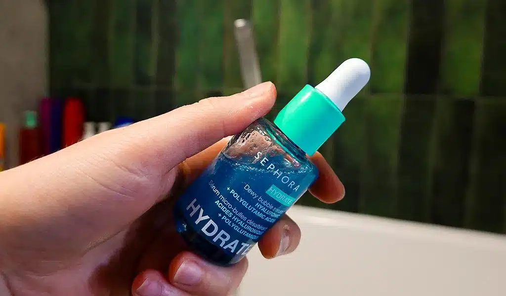Serum bąbelkowe nawadniające Sephora Collection HYDRATE trzymane w kobiecej dłoni , zielone tło