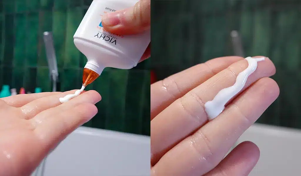 Konsystencja Vichy Capital Soleil UV-Aqua Fluid SPF50 na kobiecej dłoni, zielone tło